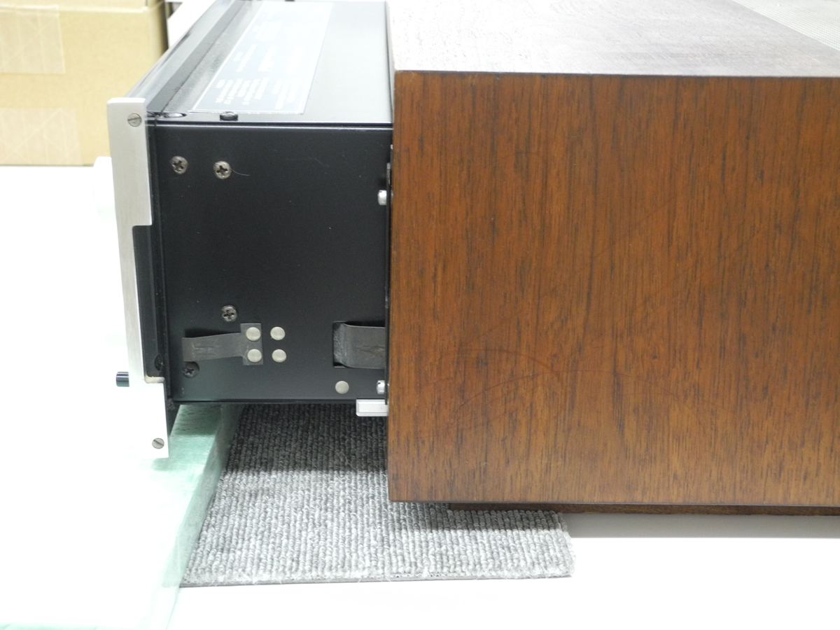 バネを指で押し込んで、アンプをウッドキャビネットの奥へ押し込む